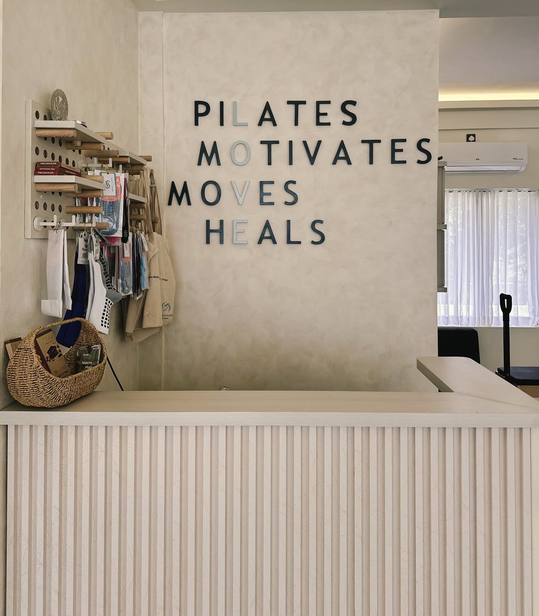 Serenity Pilates studio reception with the Pilates Motivates Moves Heals wall
